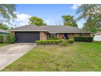 Charming brick home with a manicured lawn, lush landscaping, and attached two-car garage at 901 Vicksburg St, Deltona, FL 32725