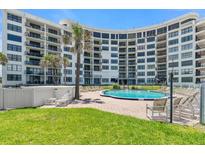 Resort-style pool surrounded by lush landscaping and lounging area in front of the condo building at 915 Ocean Shore Blvd # 8010, Ormond Beach, FL 32176