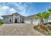 Stunning home with a three-car garage, a paver driveway, and beautifully landscaped with palms and other tropical plants at 1000 Megano Blvd, Deland, FL 32724