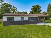 Charming single-story home boasts a gray brick and painted exterior, complemented by a lush green lawn at 1203 W 20Th St, Sanford, FL 32771