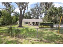 Charming single-story home featuring a well-maintained lawn and mature trees at 1402 E Voorhis Ave, Deland, FL 32724