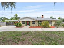 Charming single-story home featuring a quaint yellow facade, red-brick chimney, and a covered parking area at 1411 Cliff Ave, Eustis, FL 32726