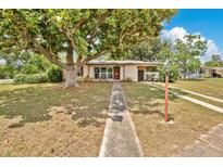 Charming single-story home with a walkway leading up to a covered porch, shaded by a large tree at 1610 Brady Dr, Deltona, FL 32725