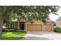 Inviting single-story home with a well-manicured lawn, mature trees, and a brick driveway leading to a two-car garage at 1632 Blue Grass Blvd, Deland, FL 32724
