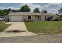 Charming single-story home featuring an attached garage, solar panels, and a well-maintained lawn at 1821 Talmadge St, Deland, FL 32724