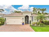 Charming home featuring a lush lawn, brick driveway, attached garage, and well-maintained landscaping at 241 Old Moss Cir, Deland, FL 32724
