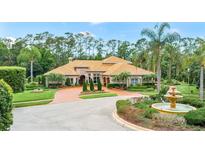 Stunning home featuring a circular driveway, lush landscaping, and a beautiful fountain, creating an inviting curb appeal at 3592 Grande Tuscany Way, New Smyrna Beach, FL 32168