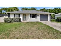 Charming single-story home features a well-maintained lawn, gray roof and an attached one car garage at 414 Lancaster Ave, Orange City, FL 32763