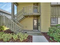 Inviting exterior view of the condo featuring a quaint walkway and staircase to upper level unit at 600 N Boundary Ave # 110A, Deland, FL 32720