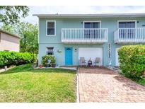 Charming two-story townhome featuring a light blue exterior, balcony, brick driveway and well-manicured lawn at 721 Laurel Bay Cir, New Smyrna Beach, FL 32169