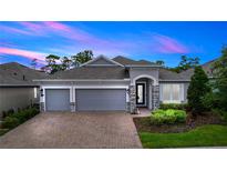 Charming single-story home with a brick driveway, three-car garage, and landscaped yard at 1227 Victoria Hills N Dr, Deland, FL 32724