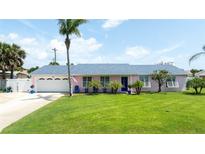 Charming pink home featuring a well-manicured lawn, palm trees, and blue accents, creating a welcoming curb appeal at 179 Ann Rustin S Dr, Ormond Beach, FL 32176