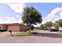 Beige home with a large garage, brick driveway, well maintained lawn, and mature trees at 201 Walter Stevens Way, Deland, FL 32724
