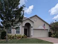 Charming single-story home with a well-manicured lawn and a welcoming two-car garage and American flag at 223 W Fiesta Key Loop, Deland, FL 32720