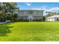Inviting two-story home featuring a large front yard with lush, green grass and manicured landscaping at 2250 Davis Dr, New Smyrna Beach, FL 32168