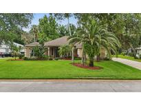 Charming single-story home with a well-manicured lawn and beautiful landscaping, including palm trees at 33 Coquina Ridge Way, Ormond Beach, FL 32174