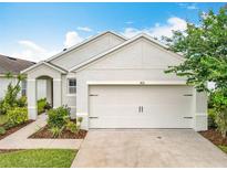 Exterior shot of the house displaying the two-car garage with a driveway and landscaping at 422 Armoyan Way, New Smyrna Beach, FL 32168