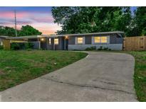 Charming one-story home with a long driveway and inviting curb appeal at dusk at 5204 Van Aken Dr, Orlando, FL 32808