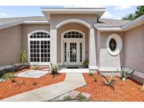 Stunning front entrance with an arched doorway, double doors and beautiful landscaping at 570 Cypress Ave, Orange City, FL 32763