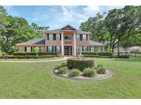 Elegant brick two-story home featuring a manicured lawn, decorative fountain, and lush landscaping at 1020 Orange Camp Rd, Deland, FL 32724