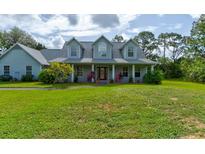 Inviting two-story home with a charming front porch and lush green lawn at 1383 Tumblin Dr, New Smyrna Beach, FL 32168