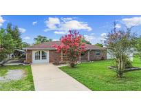 Charming brick home featuring a well-maintained lawn and blooming pink flowers in the front yard at 1702 Palmetto Ave, Deland, FL 32724