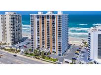 Coastal condo building featuring a manicured lawn, palm trees, and a convenient parking area at 3003 S Atlantic Ave # 3A2, Daytona Beach Shores, FL 32118