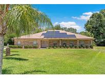 Charming brick home featuring a well-manicured lawn, complemented with solar panels for energy efficiency at 519 Donaldson Dr, Debary, FL 32713