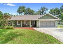 Charming single-story home with a well-manicured lawn, inviting curb appeal and a screen enclosed garage at 552 Hamlet Dr, Port Orange, FL 32127