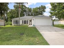 Charming single-story home featuring a manicured lawn, two car garage and mature trees at 613 John Thomas Ave, Deland, FL 32724