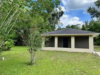 Single story home with neutral toned paint and green lawn surrounded by trees at 632 W Hubbard Ave, Deland, FL 32720