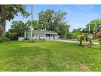 Charming home with a lush green lawn, mature trees, and beautiful landscaping at 812 Faulkner St, New Smyrna Beach, FL 32168