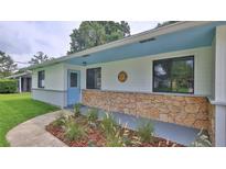 Charming front porch with stone accent wall, blue door, and landscaped garden bed at 1017 Chippewa Trl, Daytona Beach, FL 32117
