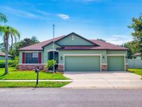 Inviting one-story home features a well-manicured lawn, three-car garage, and beautiful desert-toned color palette at 112 Tuscany Bend St, Daytona Beach, FL 32117