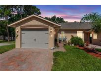 Charming single-story home showcasing a well-maintained lawn, brick driveway, and attached two-car garage at 118 Tuscany Villas Dr, Edgewater, FL 32141