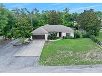 Beautiful single-story home with a well-manicured lawn, mature trees, and a two-car garage at 1734 Magnolia Ave, Deland, FL 32724