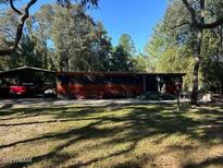 Exterior view of the house with a screened in porch and covered carport at 17531 Ne 139Th Ave, Fort Mc Coy, FL 32134