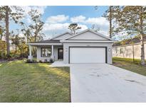 Charming one-story home with a well-manicured lawn, gray paint, and a two-car garage at 1856 9Th Ave, Deland, FL 32724