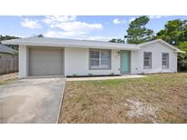Charming single-story home with a gray garage door, white exterior, and bright blue front door at 2831 Fifer Dr, Deltona, FL 32738