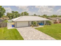Charming single-story home featuring a metal roof, lovely landscaping, brick paver driveway, and attached garage at 3324 Royal Palm Dr, Edgewater, FL 32141
