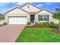 Charming single-story home featuring a well-manicured lawn, brick driveway, and blue shutters at 33436 Shutterfly Way, Sorrento, FL 32776