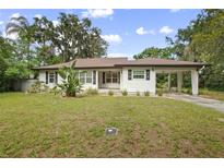 Charming single-story home with white siding, dark shutters, carport, and well-maintained front lawn at 431 S Stone St, Deland, FL 32720