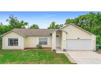 Charming single-story home featuring an attached garage, well-maintained lawn, and light yellow siding at 685 N Firwood Dr, Deltona, FL 32725