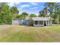 Charming single-story home with a screened porch and detached garage surrounded by a lush green lawn at 710 W May St, Deland, FL 32720
