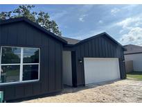 Modern dark gray home with a white garage door and trimmed window at 822 W 24Th St, Sanford, FL 32771