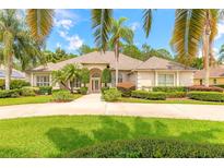 Charming home with a circular driveway, lush landscaping, and mature palm trees at 15 Cambridge Trce, Ormond Beach, FL 32174