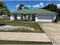 Charming single-story home with a well-manicured lawn, attractive landscaping, and a green metal roof at 1973 S Old Mill Dr, Deltona, FL 32725