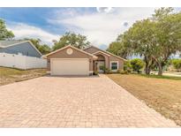 Charming single-story home with a brick driveway and well-maintained lawn and mature trees at 198 Heather Lane Dr, Deltona, FL 32738