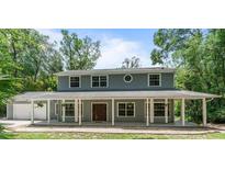 Charming two-story home featuring a large, covered front porch with white pillars and a well-maintained lawn and garage at 2 E Kelly Park Rd, Apopka, FL 32712