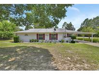 Charming single-story home featuring a well-maintained front yard and a convenient covered parking area at 25305 Mardon Cir, Paisley, FL 32767